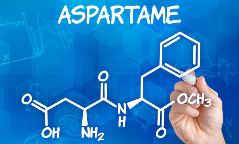 23076593 hand with pen drawing the chemical formula of aspartame